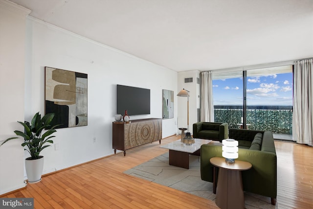 living area with light wood finished floors, visible vents, floor to ceiling windows, and crown molding