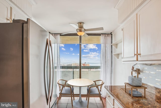 dining space featuring ceiling fan, light tile patterned floors, and a wall of windows