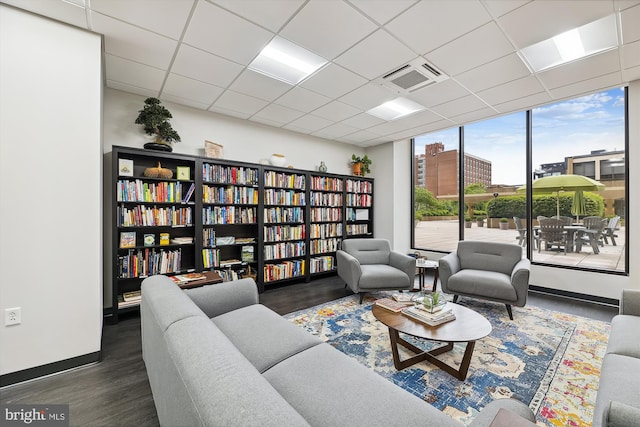 living room featuring a paneled ceiling, dark wood-style flooring, visible vents, and a city view