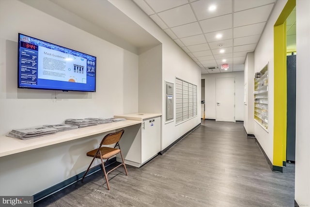 office area with mail area, baseboards, a drop ceiling, and wood finished floors