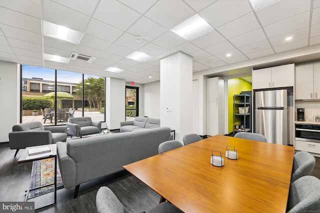 dining room with floor to ceiling windows, visible vents, a drop ceiling, and wood finished floors