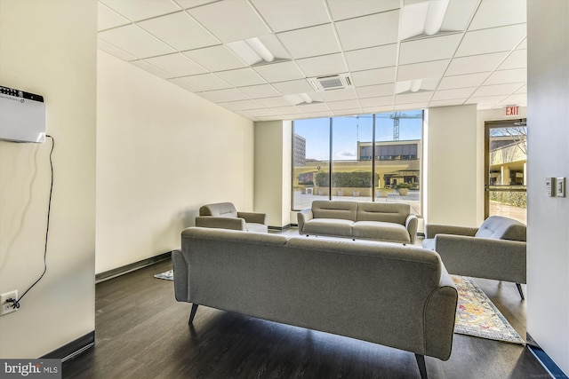 living area with dark wood-type flooring, a wealth of natural light, visible vents, and a paneled ceiling