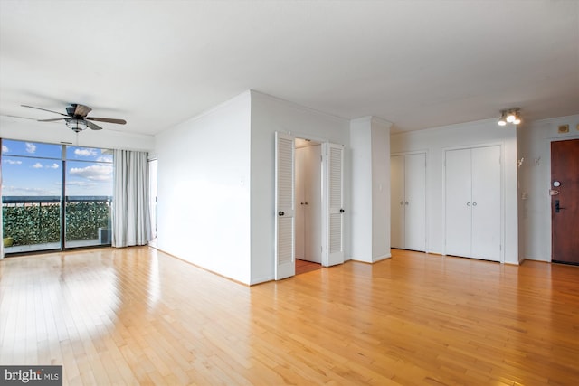 unfurnished room with light wood-type flooring, baseboards, floor to ceiling windows, and a ceiling fan