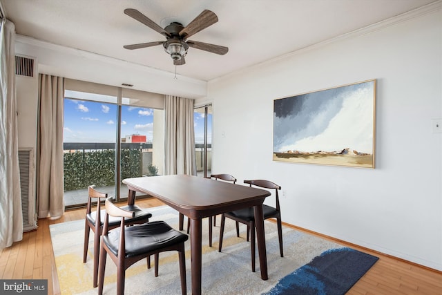 dining area featuring visible vents, ornamental molding, light wood-style floors, a ceiling fan, and baseboards