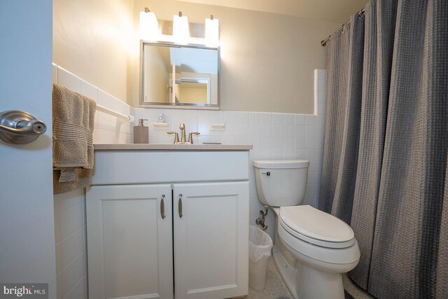 bathroom with a shower with shower curtain, vanity, toilet, and tile walls