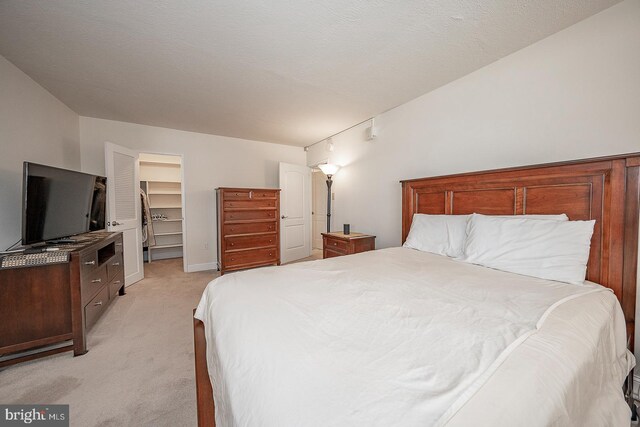 carpeted bedroom featuring a textured ceiling, a walk in closet, and a closet