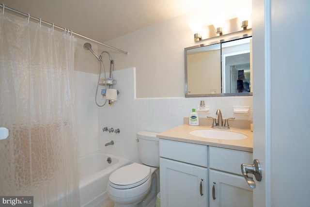 full bathroom featuring vanity, toilet, shower / bath combo with shower curtain, and tile walls