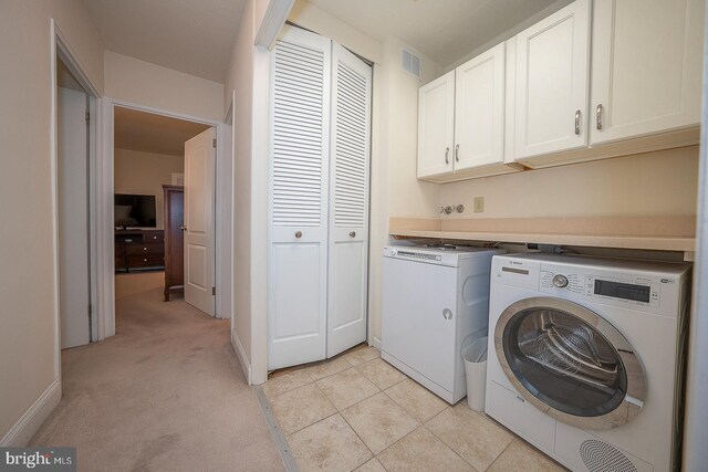 laundry room with washing machine and dryer, light carpet, and cabinets