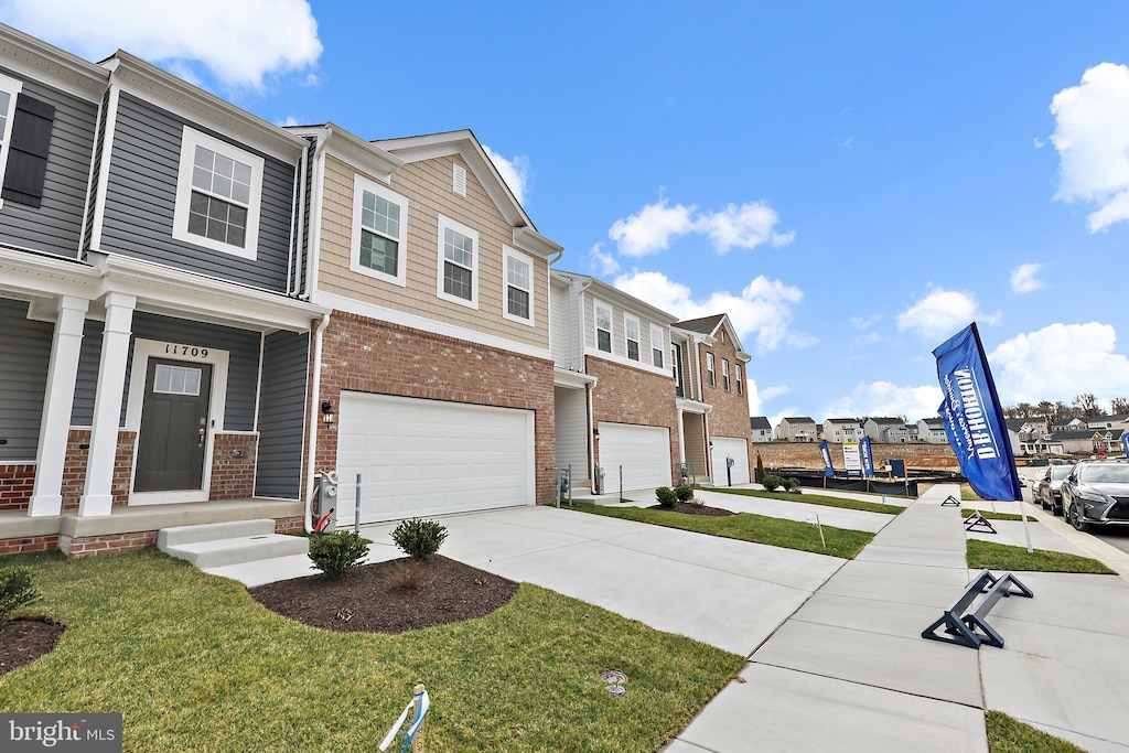 townhome / multi-family property with a front yard, a garage, and a porch