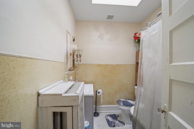 washroom with a skylight and tile patterned flooring