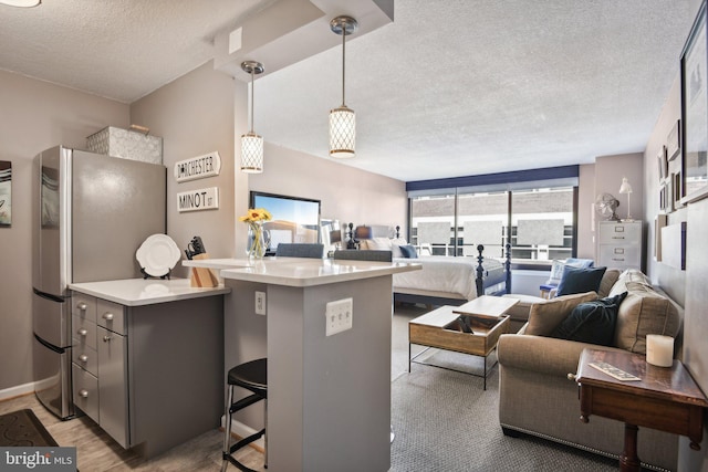 kitchen with kitchen peninsula, a breakfast bar area, stainless steel fridge, and a textured ceiling