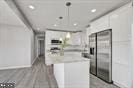 kitchen with a center island, wood-type flooring, white cabinetry, and stainless steel refrigerator with ice dispenser