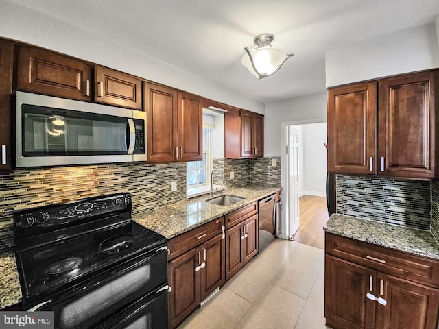 kitchen featuring light stone counters, light tile patterned floors, stainless steel appliances, and sink