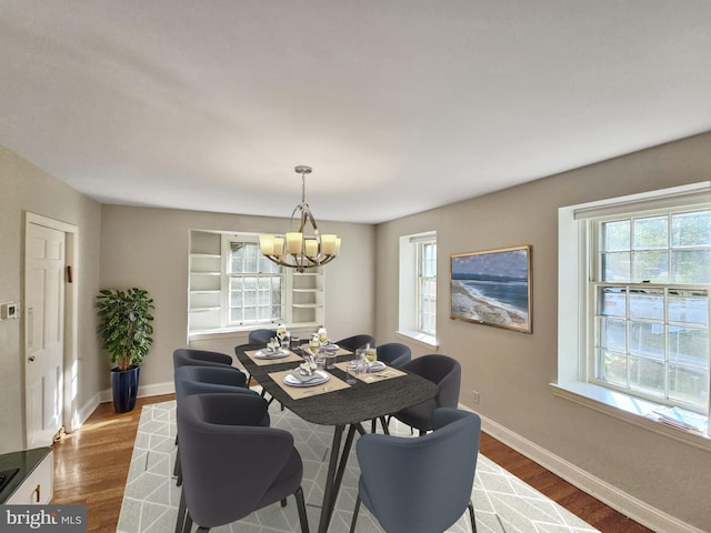 dining room with hardwood / wood-style flooring, built in features, and a chandelier