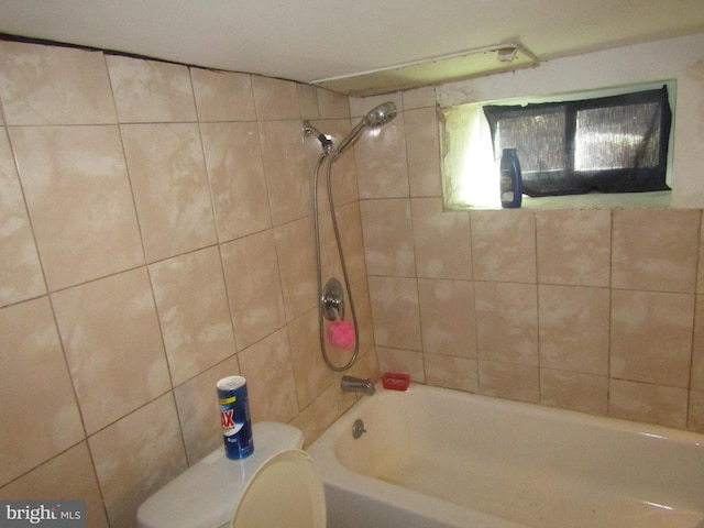 bathroom with toilet and tiled shower / bath