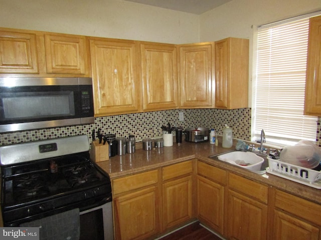 kitchen with black gas range, backsplash, plenty of natural light, and sink