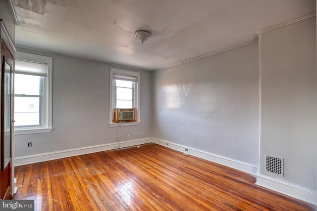 spare room with plenty of natural light, wood-type flooring, and ornamental molding