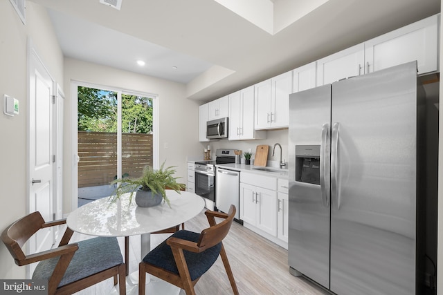 kitchen featuring sink, white cabinets, stainless steel appliances, and light hardwood / wood-style floors