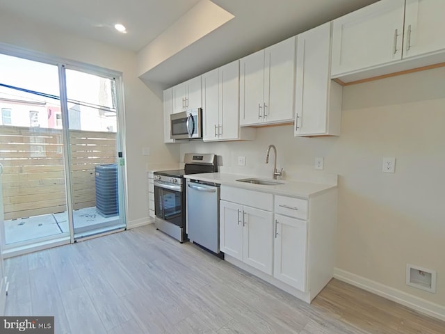 kitchen with sink, white cabinets, stainless steel appliances, and light hardwood / wood-style flooring