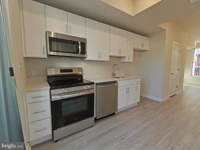 kitchen featuring white cabinets, sink, appliances with stainless steel finishes, and light hardwood / wood-style flooring