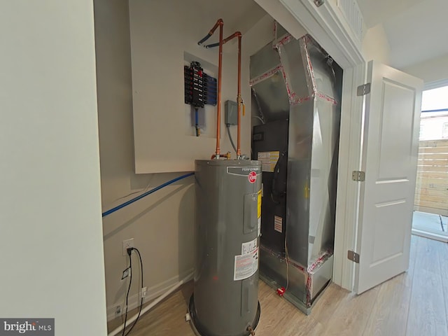 utility room with heating unit and electric water heater