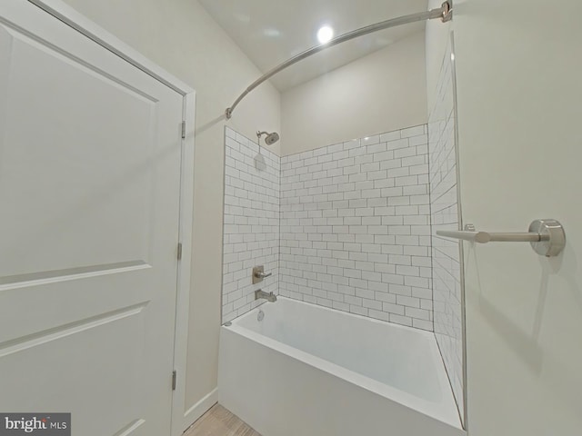 bathroom featuring wood-type flooring and tiled shower / bath