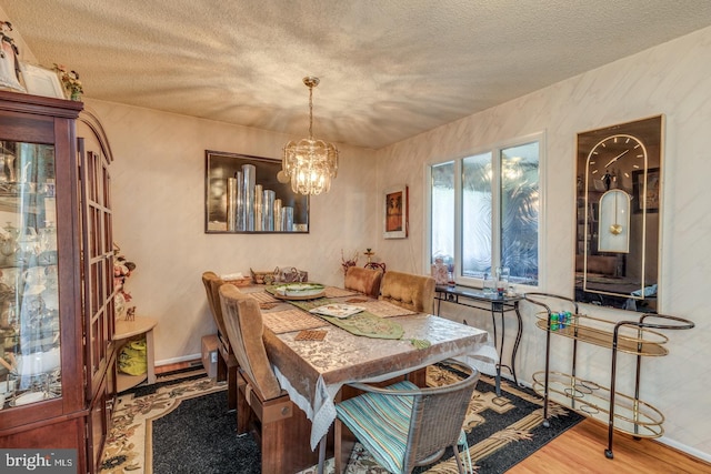 dining room with hardwood / wood-style floors, a textured ceiling, and a chandelier