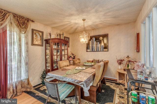 dining area featuring hardwood / wood-style floors, a textured ceiling, and a chandelier