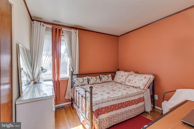 bedroom with wood-type flooring and ornamental molding