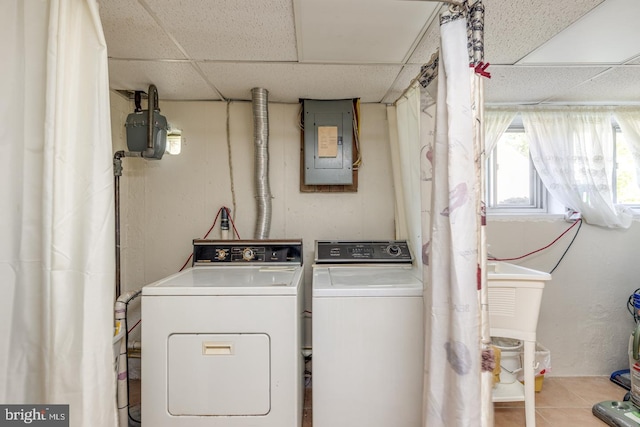 washroom featuring washing machine and clothes dryer, electric panel, and light tile patterned floors