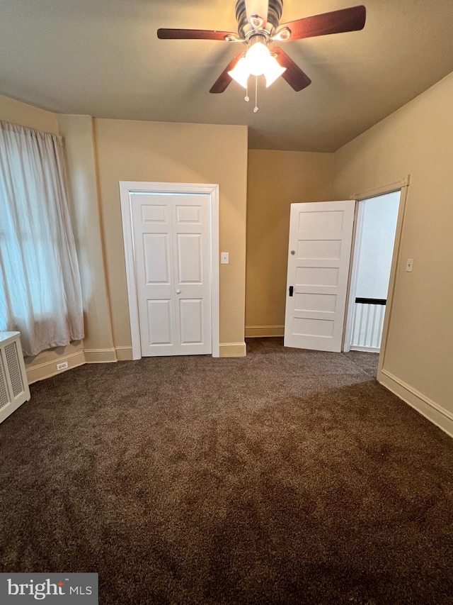 unfurnished bedroom featuring ceiling fan, a closet, and dark carpet