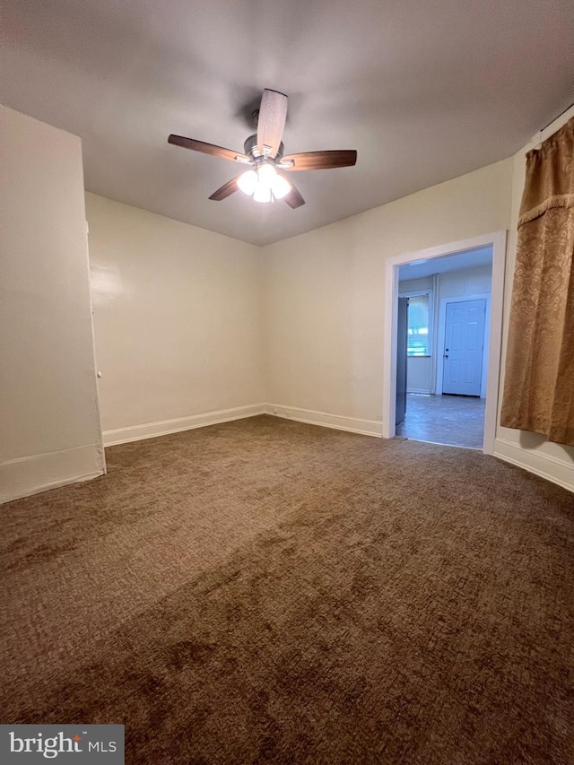 spare room featuring dark colored carpet and ceiling fan