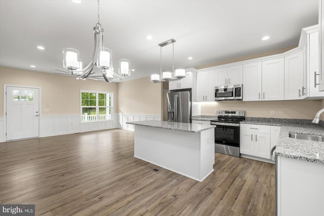 kitchen featuring pendant lighting, a kitchen island, dark hardwood / wood-style floors, white cabinets, and appliances with stainless steel finishes