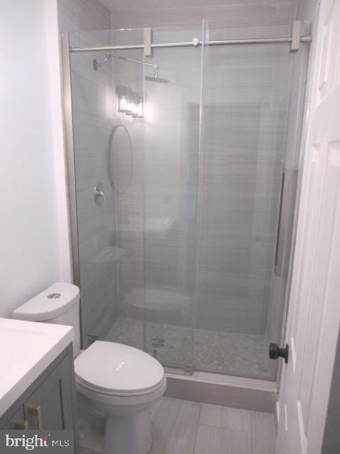 bathroom featuring an enclosed shower, vanity, and toilet