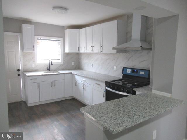 kitchen with white cabinets, dark wood-type flooring, kitchen peninsula, wall chimney range hood, and black range with electric cooktop