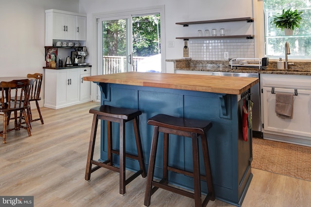 kitchen featuring butcher block countertops, sink, light hardwood / wood-style floors, and white cabinetry