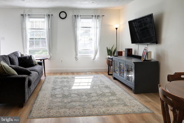 living room with a textured ceiling, light hardwood / wood-style flooring, and plenty of natural light