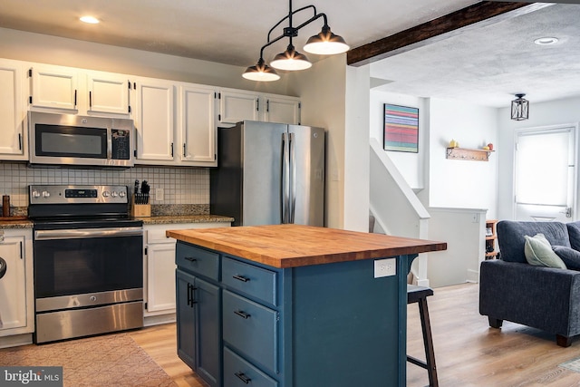 kitchen featuring appliances with stainless steel finishes, white cabinetry, a breakfast bar area, and decorative light fixtures