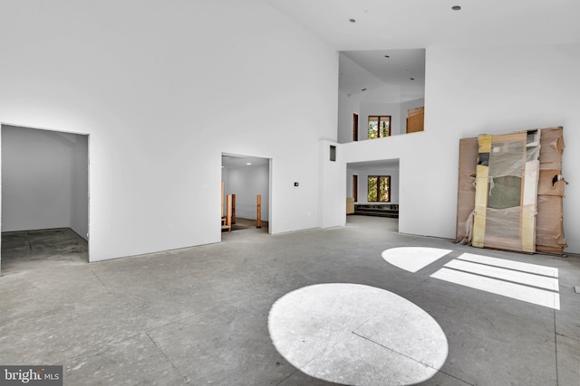 living room with high vaulted ceiling and concrete floors