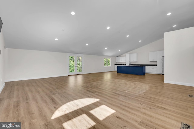 unfurnished living room with sink, lofted ceiling, and light hardwood / wood-style floors