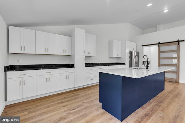 kitchen featuring sink, white cabinetry, a barn door, and vaulted ceiling