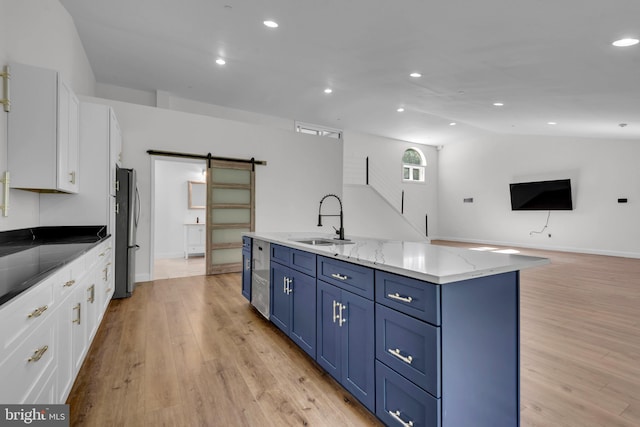 kitchen featuring a barn door, a kitchen island with sink, sink, stainless steel appliances, and white cabinets