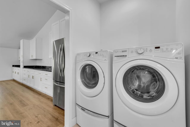 laundry room with washer and dryer and light hardwood / wood-style floors