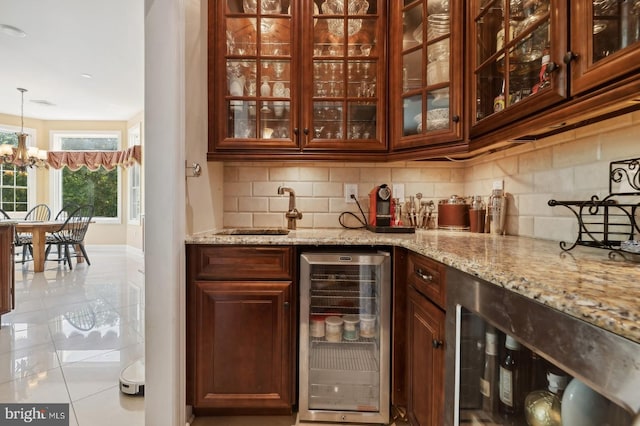 bar with hanging light fixtures, beverage cooler, light stone counters, an inviting chandelier, and sink