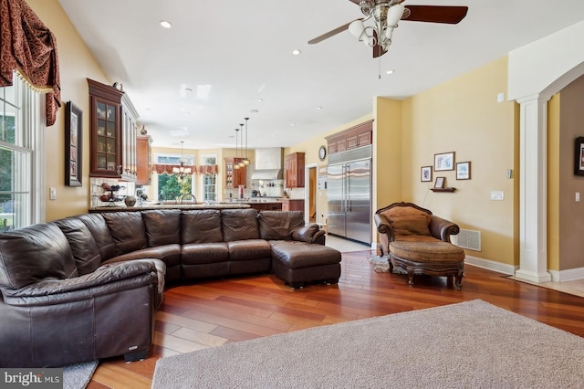 living room with ceiling fan, hardwood / wood-style flooring, and decorative columns