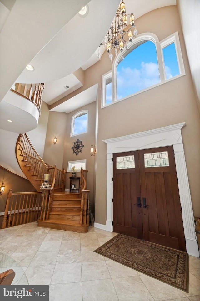 tiled entrance foyer with a high ceiling and a notable chandelier