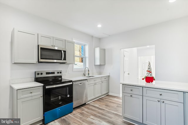 kitchen featuring gray cabinets, sink, light hardwood / wood-style floors, and appliances with stainless steel finishes