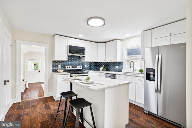 kitchen featuring white cabinets, a center island, appliances with stainless steel finishes, and dark hardwood / wood-style floors