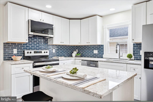 kitchen with appliances with stainless steel finishes, decorative backsplash, sink, and white cabinets