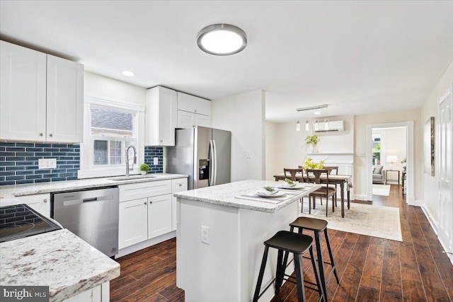 kitchen with a kitchen island, sink, stainless steel appliances, and white cabinets